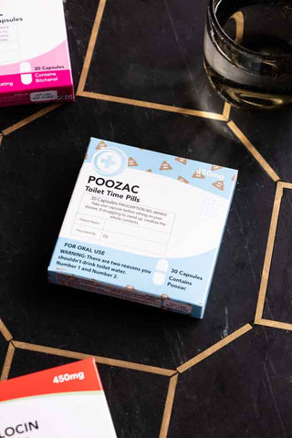 The Poozac Mints Pill Packet styled on a dark surface with some other boxes.