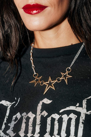 Close-up of the Gold 3 Star Necklace being worn by a model.