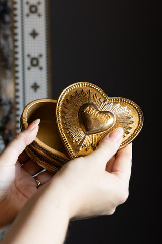 The Gold Amour Heart Trinket Box with hands  holding out the lid and box.