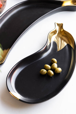 The Gold Aubergine Serving Bowl displayed with the Gold Banana Serving Bowl, styled with olives inside.