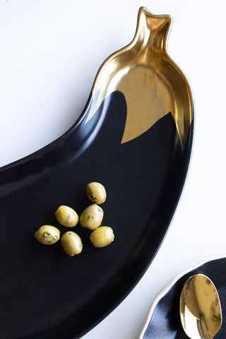 Close-up image of the Gold Aubergine Serving Bowl displayed with olives on. There is a plate and spoon in the corner of the shot.