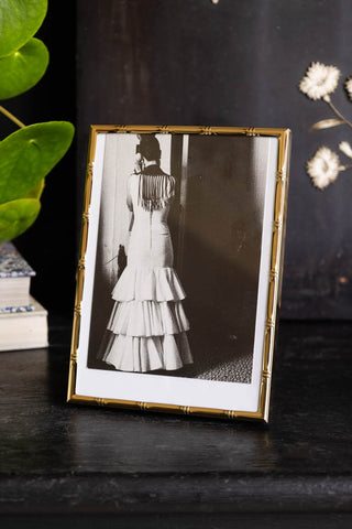 Lifestyle image of the Gold Bamboo Effect Photo Frame on a shelf with a plant