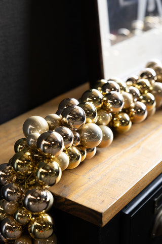 The Gold Bauble Cluster Christmas Garland displayed on a wooden console table.