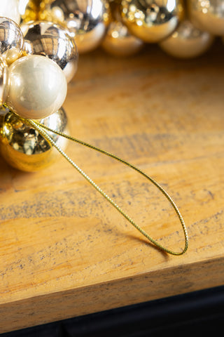 Close-up of the hanging loop on the end of the Gold Bauble Cluster Christmas Garland, displayed on a wooden surface.