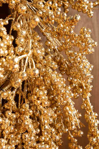 Close-up of the Gold Berry Christmas Wreath on a dark wall.