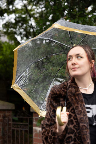 The inside of the Clear & Gold Domed Umbrella, shown outside in the rain. 