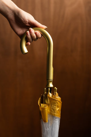 The gold handle of the Clear & Gold Domed Umbrella. 