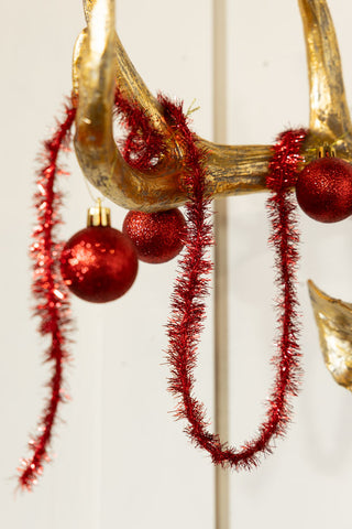 Close-up of the red tinsel/baubles on the Gold Christmas Reindeer Wall Art Decoration.