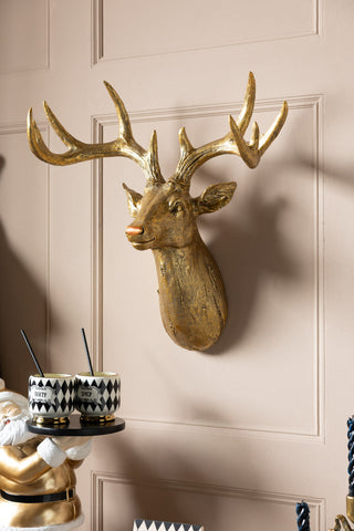 The Gold Christmas Reindeer Wall Art Decoration styled on the wall above a santa butler ornament holding some drinks.