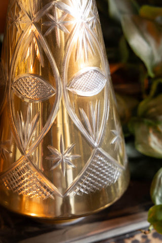 Close-up of the Gold Etched Christmas Tree Display Ornament with some greenery in the background.