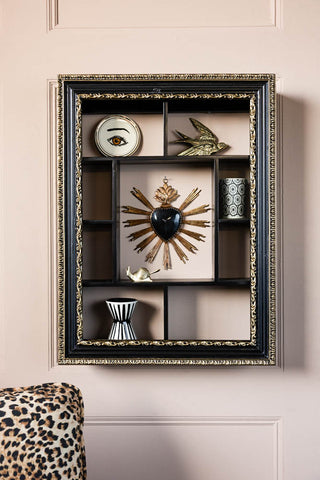 The Ornate Black & Gold Framed Wall Shelf styled with various accessories, displayed on a wall above a leopard print sofa.