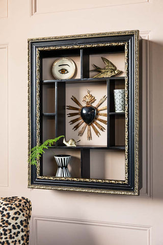 The Ornate Black & Gold Framed Wall Shelf styled with various accessories inside, styled on a wall.
