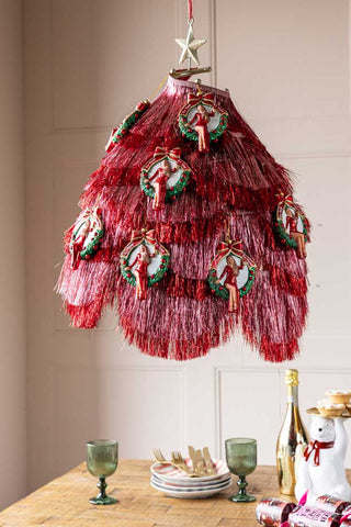 The Gold Hanging Christmas Frame for Decorations styled with various tinsel on and lots of Christmas hanging decorations, displayed above a Christmas tablescape.