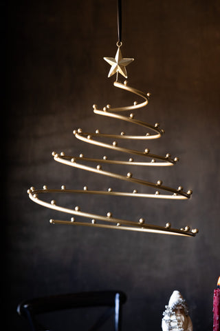The Gold Hanging Christmas Frame for Decorations hanging in front of a dark background and above a Christmas tablescape.