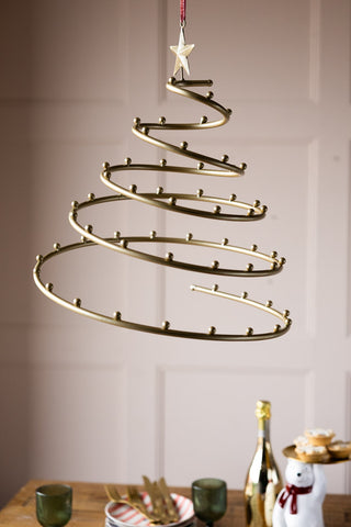 The Gold Hanging Frame for Decorations hanging in front of a plain background and above a table styled for Christmas.