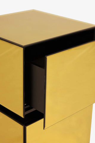 Close-up of a gold bedside table with the top drawer open.