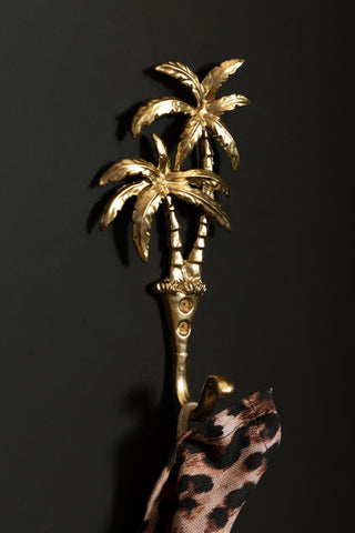 The Gold Palm Trees Wall Hook styled on a black wall, with a leopard print tea towel hanging from it.