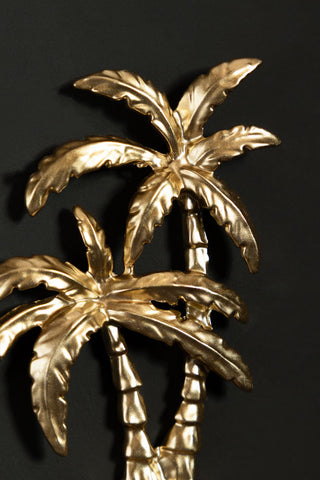 Close-up of the Gold Palm Trees Wall Hook on a black wall.