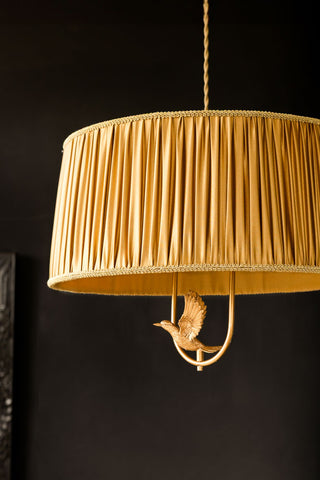 A close up of the Gold Ruched Hanging Bird Pendant Light, showing the ruched fabric shade and gold bird detail. 