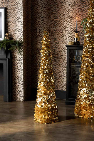 The Gold Tinsel Christmas Tree Cone - Medium shown in a leopard print living room. 