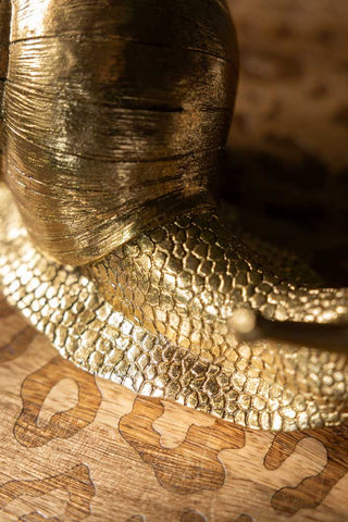 Close-up of the Gold Snail Ornament displayed on a leopard print surface.
