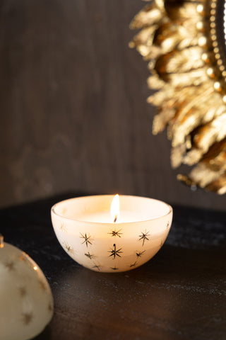 The Gold Star Christmas Candle Bauble Ornament with the lid off, lit and displayed on a dark wooden surface.