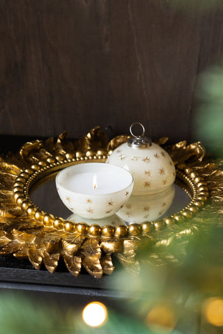 The Gold Star Christmas Candle Bauble Ornament lit and displayed on a gold decorative mirror.