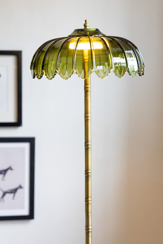 Close-up of the top of the Gold & Green Desert Palm Floor Lamp, with some art prints on the wall in the background.