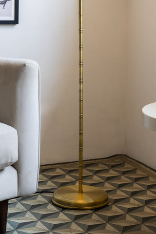 Close-up of the base of the Gold & Green Desert Palm Floor Lamp, styled on a geometric floor next to a sofa and a side table.