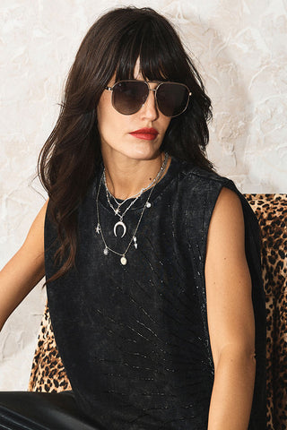The Gold & Silver Charm Layered Necklace worn by a model wearing sunglasses.