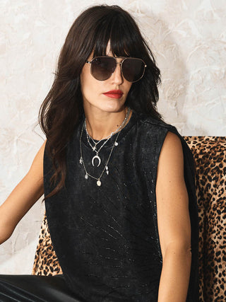 The Gold & Silver Charm Layered Necklace worn by a model wearing sunglasses.