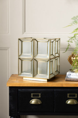 The Gold Geometric Glass Table Lamp shown with the light off on a apothecary-style console table. 