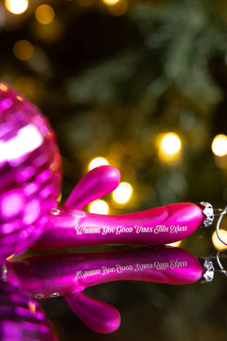 The Good Vibes Sex Toy Christmas Tree Decoration styled on a dark surface with a pink disco ball.