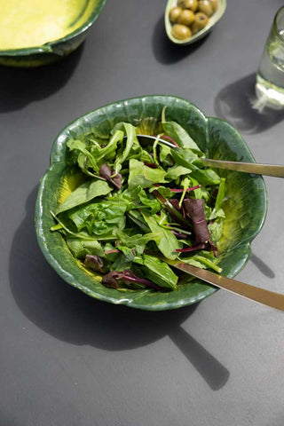 Lifestyle image of the green cabbage bowl on a dark table with salad