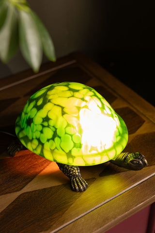The Green Speckled Glass Turtle Table Lamp shown wit the light on. 
