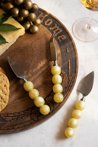 The HKLIVING Set of 3 Yellow Bobble Cheese Knives shown on a bread board with cheese and crackers. 