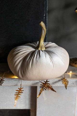 Mini ivory velvet pumpkin on a mantlepiece with fairy lights