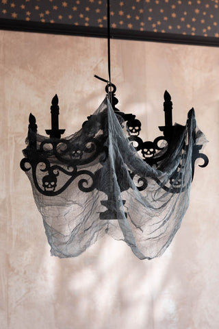 The Haunted House Paper Chandelier Decoration shown against a plaster wall with a star wallpaper border. 