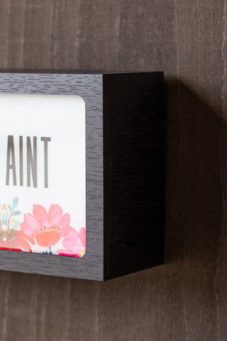 Close-up of the edge of the Home Is Where The Fuckers Aint Light Box on the wall.