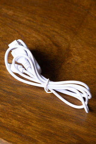 The cable supplied with the Home Is Where The Fuckers Aint Light Box displayed on a wooden surface.