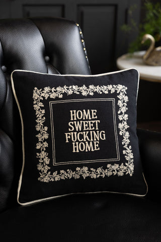 The Home Sweet Fucking Home Embroidered Cushion styled on a black sofa.