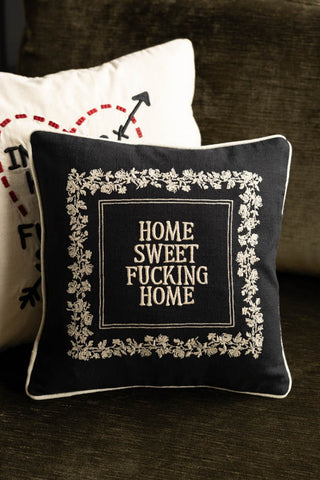 The Home Sweet Fucking Home Embroidered Cushion displayed with another cushion on a green sofa.