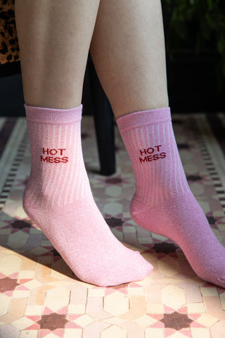 The Hot Mess Pink Glitter Socks shown on a model against a pink star tile-effect floor. 