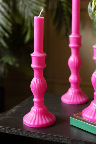 The Hot Pink Candlestick Shaped Candle - Medium showing the candle unlit with a tall version of the candle in the background.
