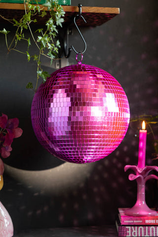 The Hot Pink Disco Ball hanging from a shelf, reflecting light onto various accessories around it.