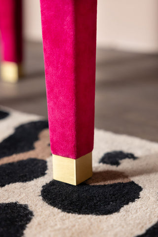 The gold tipped legs of the Hot Pink Velvet Dressing Table & Stool,