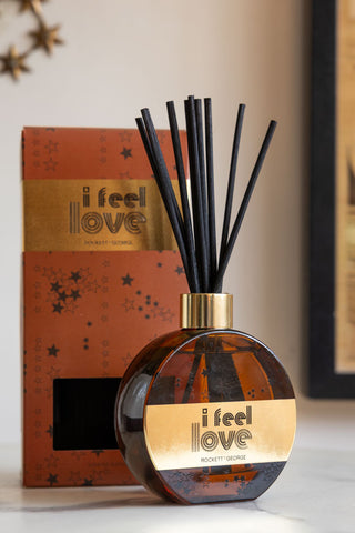 The I Feel Love Cedarwood & Frankincense Reed Diffuser with th ebox, displayed on a marble surface.