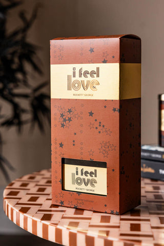 The I Feel Love Cedarwood & Frankincense Reed Diffuser displayed in the box, on a patterned table with some other accessories.