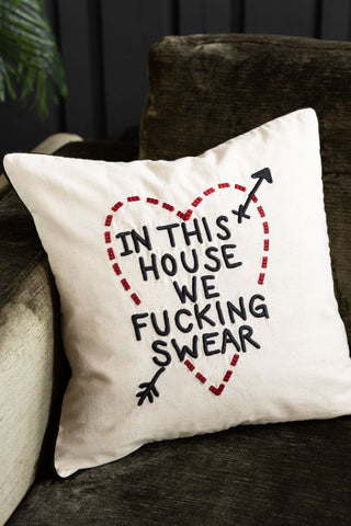The In This House We Swear Embroidered Cushion on a velvet sofa.