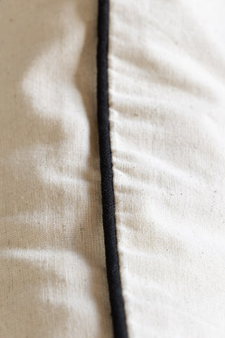Close-up of the piped edge of the In This House We Swear Embroidered Cushion.